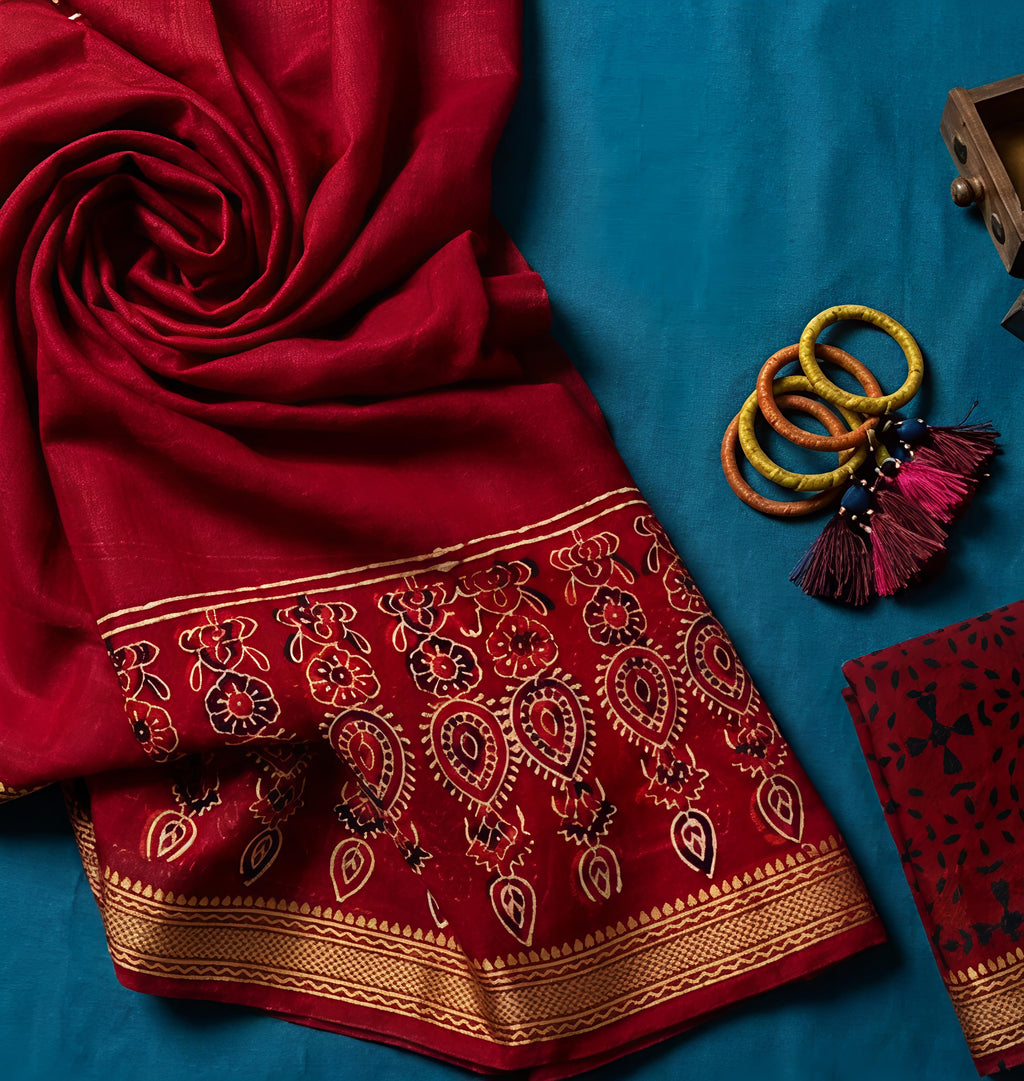 Red embroidered saree with gold patterns on a blue background
