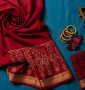 Red embroidered saree with gold patterns on a blue background